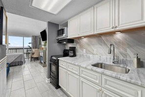 A modern kitchen with white cabinetry, a stainless steel sink, and a built-in microwave.