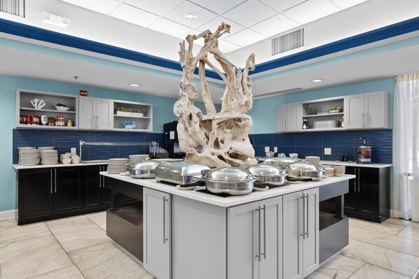 Une cuisine moderne dotée d’un îlot central, de meubles blancs et d’une sculpture décorative en forme d’os.