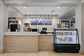 A modern coffee shop interior with a counter, espresso machines, a refrigerated display case, and menu boards.