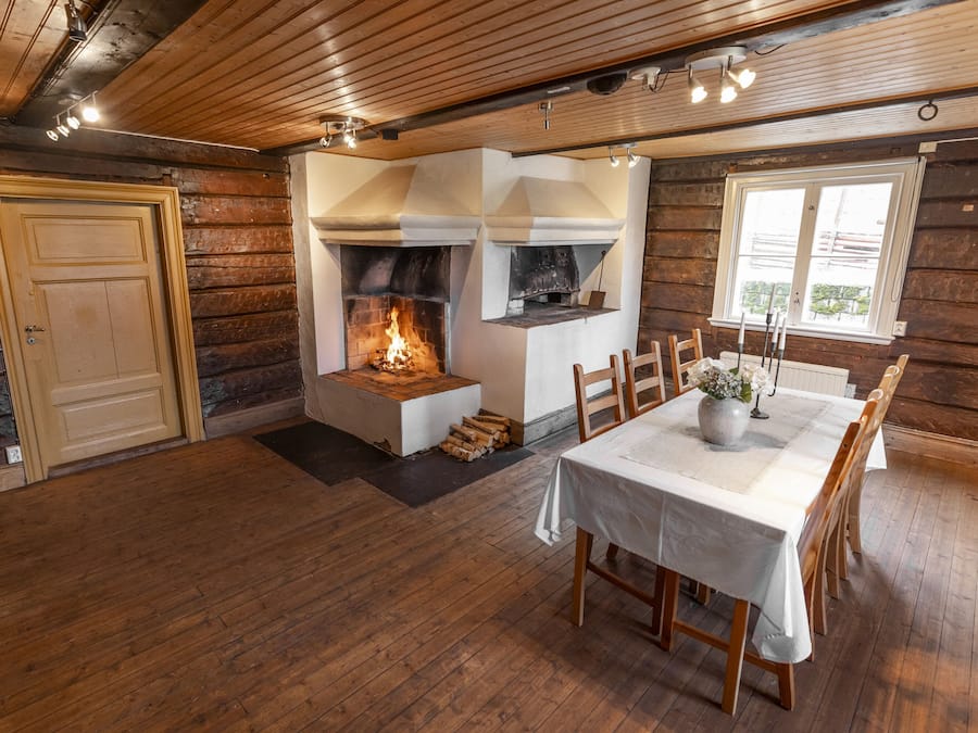 Ein rustikales Blockhaus-Interieur mit Kamin, Holztisch und Stühlen.