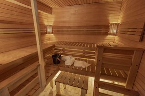 Una sauna con bancos de madera, un cubo y toallas.