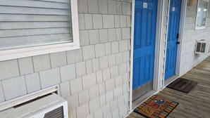 A building with a light gray exterior, blue doors, and a wooden deck. - Ocean Therapy (Carolina Beach)