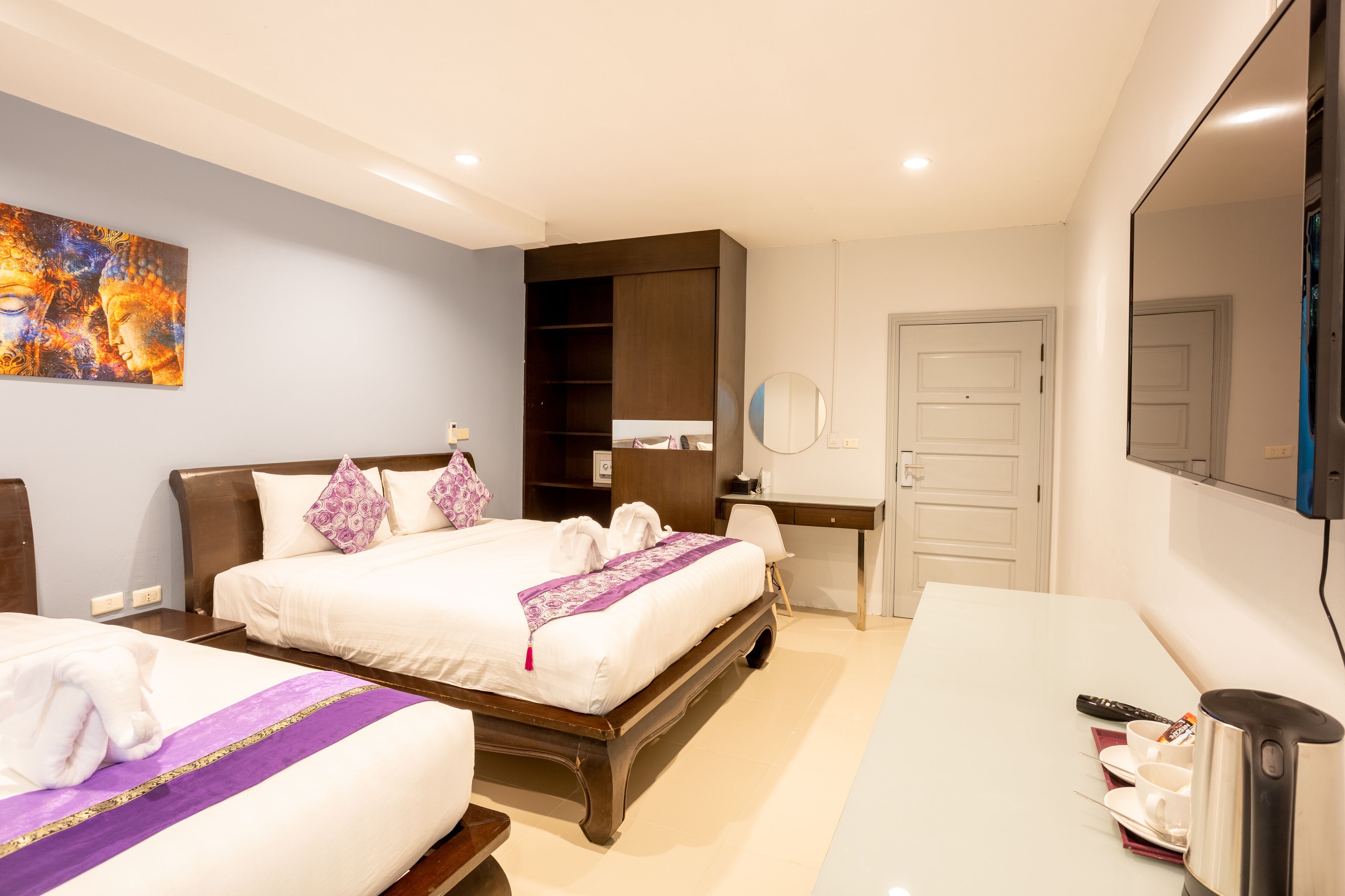 Habitación de hotel con dos camas, un escritorio, un espejo y un televisor.