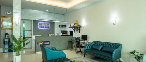 A hotel reception area with a reception desk, a blue sofa, and a coffee machine.