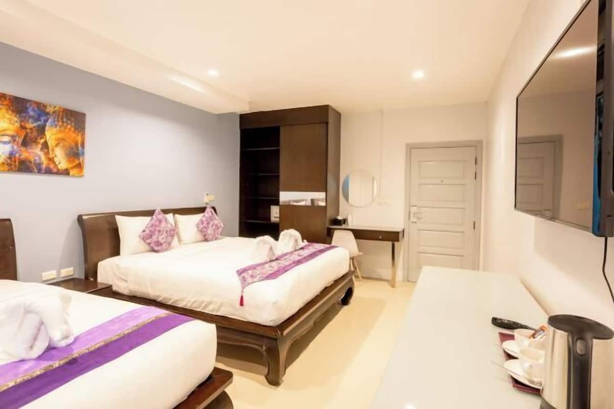 A hotel room with two beds, a desk, a chair, a TV, and a painting on the wall.