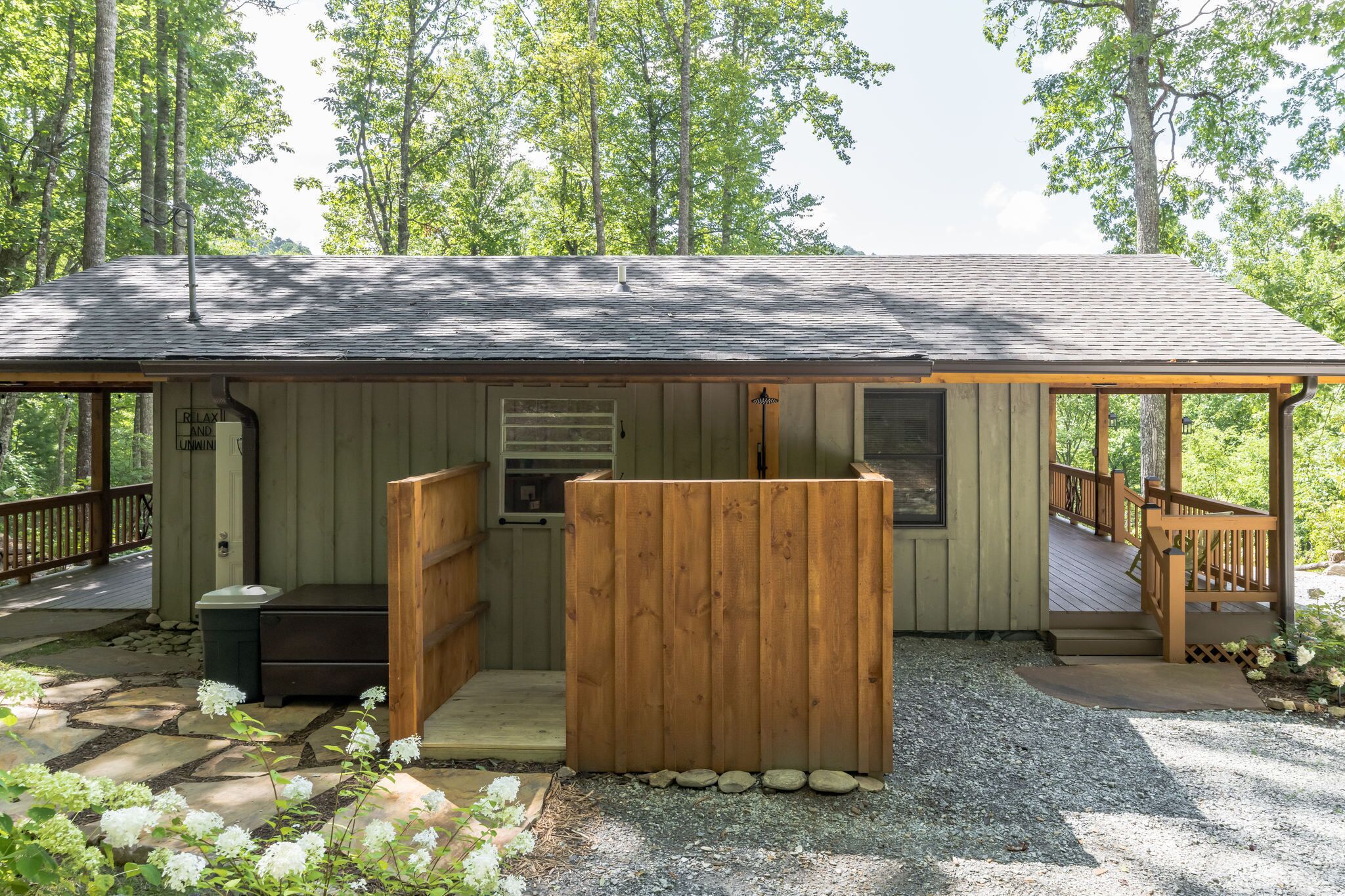 A wooden cabin with a porch, a small deck, and a covered seating area.