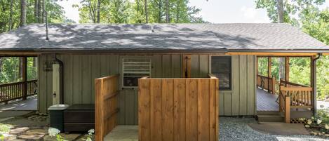 A wooden cabin with a porch, a small deck, and a covered seating area.