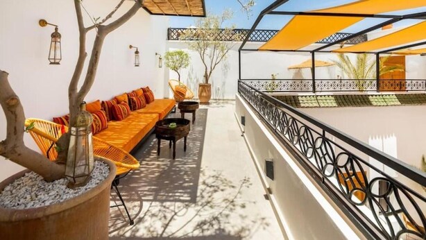 Un área de estar al aire libre con sofá, sillas y una mesa, protegida por una marquesina.