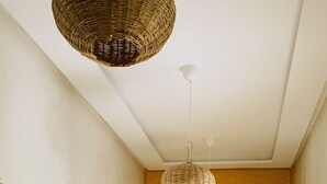 Un dormitorio con cama, una silla, una mesa y una lámpara colgante.