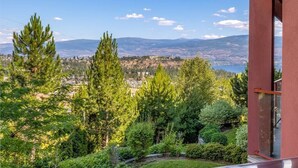 A balcony with a view of a cityscape, mountains, and a body of water.