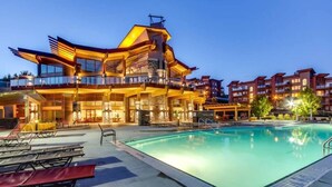 A modern hotel with a pool, outdoor seating, and a large building with balconies.