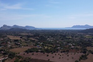 An aerial view of a coastal town with a mix of residential and agricultural areas, surrounded by mountains and a large body of water. - Villa Cal Roma with swiming pool in the countryside (Pollensa)