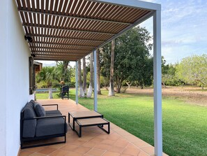 A covered patio with a seating area, a grill, and a view of a grassy yard with trees. - Villa Cal Roma with swiming pool in the countryside (Pollensa)