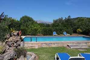 A swimming pool with lounge chairs and a rocky landscape.