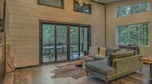 Relax in a spacious living area with a sofa set, coffee table, and rug, leading to an outdoor deck.