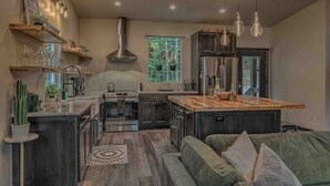 A modern kitchen with dark cabinetry, a central island, and pendant lighting. - Brand New Relaxing Mountain Retreat 
 (Talking Rock)
