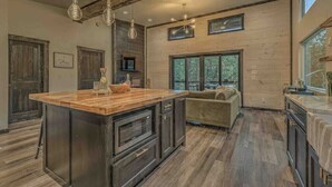 A spacious kitchen with a large island, wooden flooring, and a cozy seating area with a couch. - Brand New Relaxing Mountain Retreat 
 (Talking Rock)