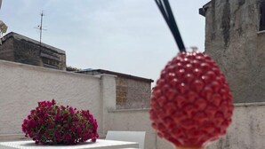 A white table with a decorative red object and a potted plant. - CALA APARTAMENT (Palermo)