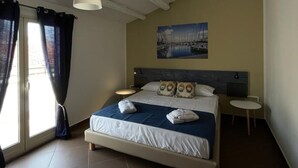 A bedroom with a bed, a painting, a bedside table, and a chair. - CALA APARTAMENT (Palermo)