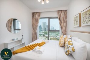 A hotel room with a bed, a bedside table, a mirror, a window with curtains, and artwork on the wall. - Vogue | Downtown with Direct Access to Dubai Mall (Dubai)