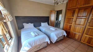 A room with two beds, a wooden wardrobe, and a window with curtains. - Full Moon Guest House (Mbombela)