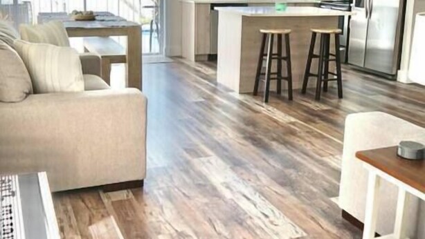 Una cocina moderna con armarios blancos, una isla central con taburetes e iluminación colgante.