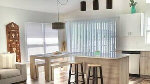 Una cocina moderna con una isla central, taburetes de bar, luces colgantes y un ventilador de techo.