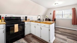 Une cuisine avec des armoires blanches, une cuisinière noire et un plan de travail en bois.