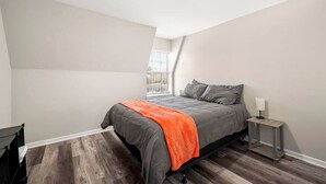 Une chambre à coucher avec un lit, une table de chevet, une fenêtre et un luminaire au plafond.