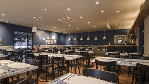 A spacious restaurant with multiple tables and chairs, a counter with a menu, and pendant lights on the ceiling. - Estúdio Aconchegante, Metrô, Piscina, Sauna, AC (São Paulo)