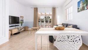Ein modernes Wohnzimmer mit Flachbildfernseher, Esstisch und einer Couch.