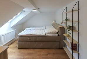 Quarto com beliche, claraboia e estantes embutidas com livros e uma planta.