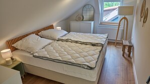 Ein Schlafzimmer mit einem Bett, Nachttischen, einer Lampe, einem Fenster und einer Heizung.
