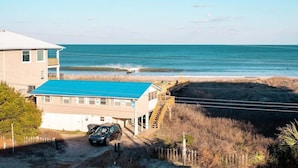 Un bâtiment situé en bord de mer, avec un toit bleu, un espace de stationnement et une vue sur l’océan.