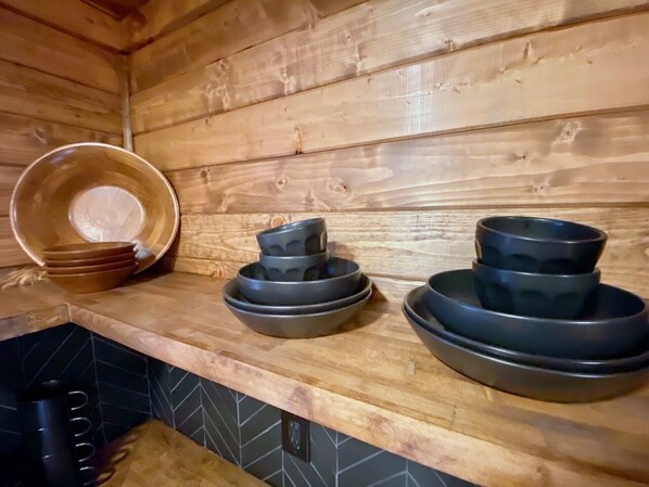 A wooden interior with a kitchen counter displaying stacked bowls and plates.