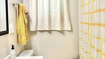 A bathroom with a white sink, a toilet, and a shower curtain.
