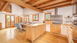 Una cocina amplia con armarios de madera, una estufa de acero inoxidable y una zona de comedor de madera con una mesa y sillas.