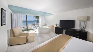 A modern hotel room with a large bed, a TV, a bathtub, and a view of the beach. - The Sens Riviera By Oasis (Akumal)