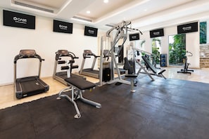 A gym with treadmills, a bench press, and weight machines, with 'OASIS HOTELS & RESORTS' signs on the walls. - The Sens Riviera By Oasis (Akumal)