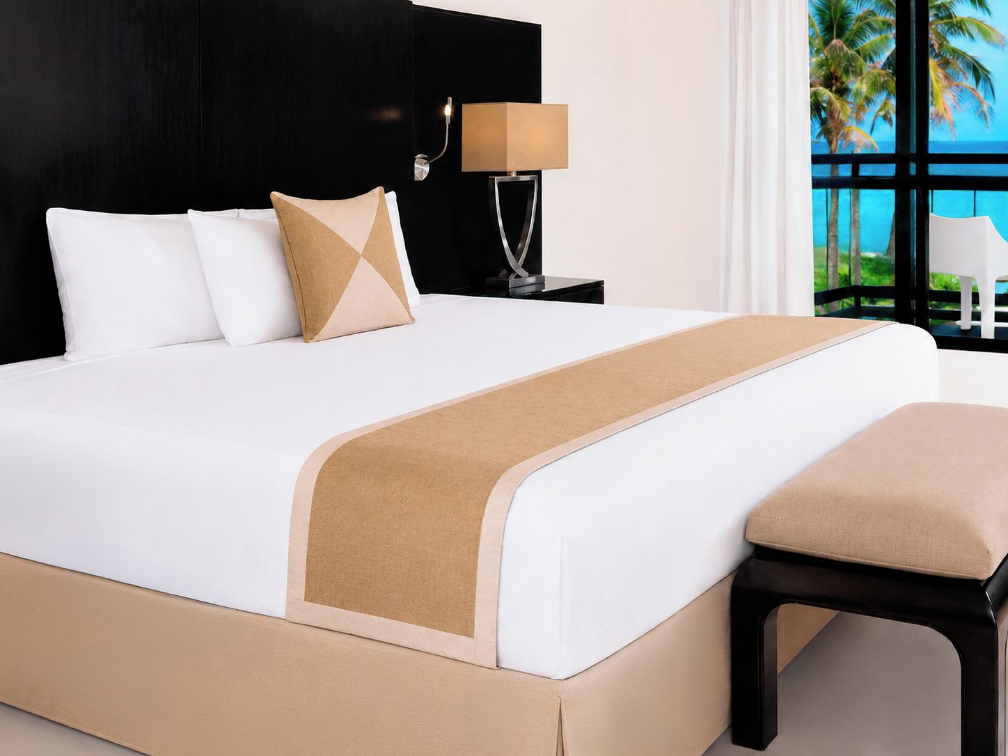 Una habitación de hotel con cama, mesita de noche, lámpara y vista al océano.