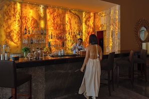 A bar area with a marble wall and a bartender serving a customer.