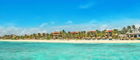 A beach resort with clear turquoise water, white sandy beach, and overwater bungalows.