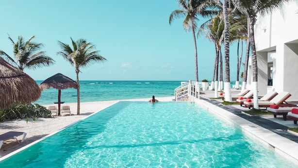 A clear blue pool with lounge chairs and palm trees, overlooking the ocean. - The Sens Riviera By Oasis (Akumal)