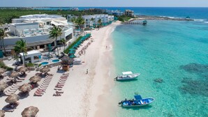 A beach resort with a long sandy beach, clear turquoise waters, and a row of sun loungers and umbrellas. - The Sens Riviera By Oasis (Akumal)