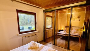 A room with two beds, a window, and a view of the outside. - Gemütlicher Bungalow in Ruhiger Lage mit Traumhafter Aussicht für 2-6 Personen (Dipperz)
