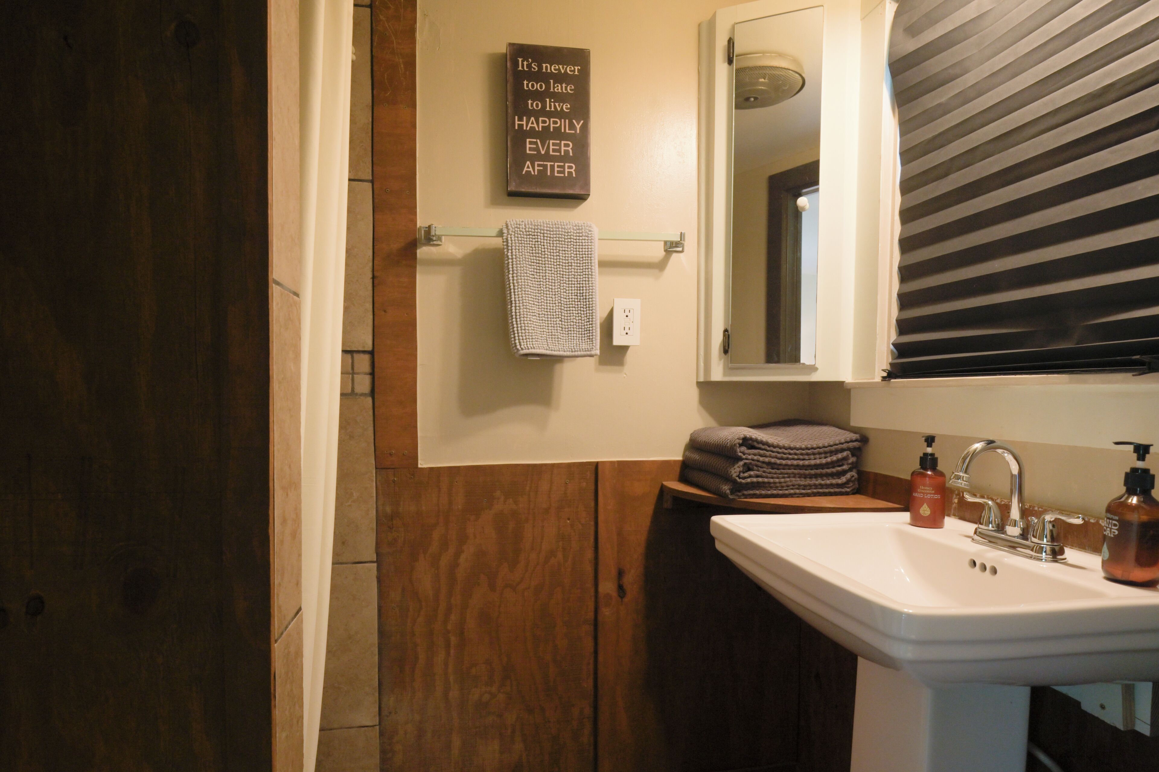 Un baño con tocador de madera, un lavabo blanco, un espejo y un perchero para toallas.