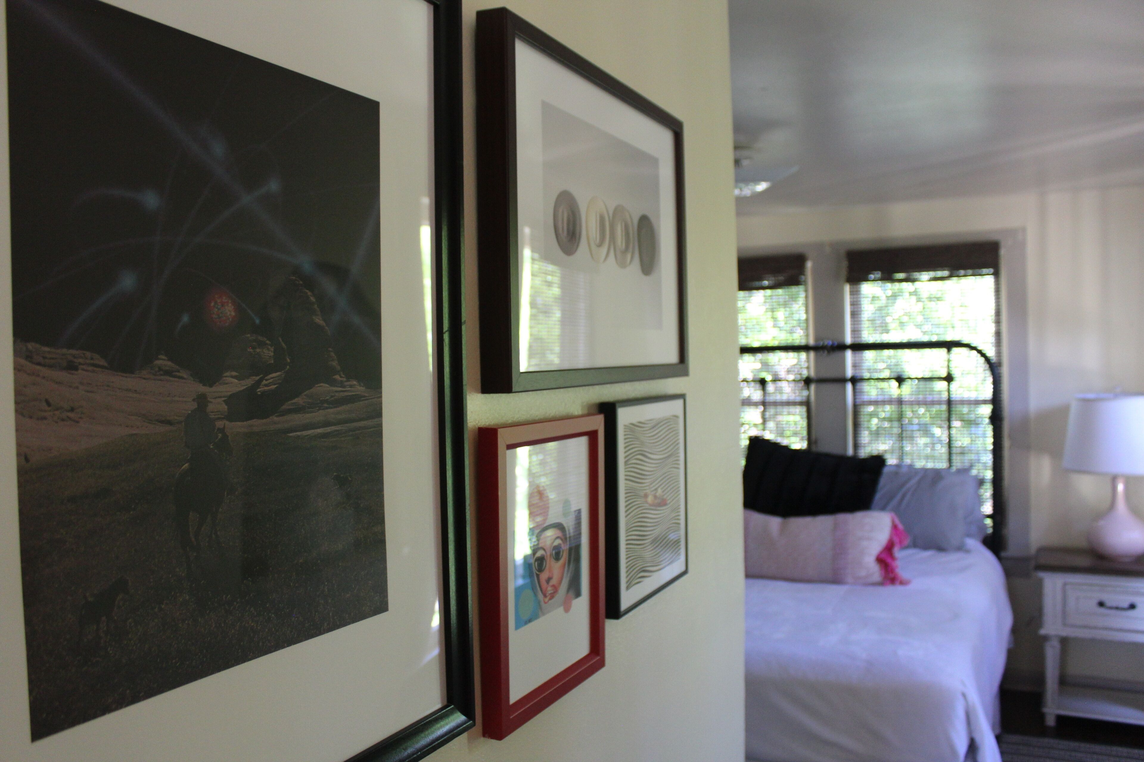 A bedroom with a bed, a nightstand, and wall-mounted artwork.