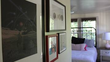 A bedroom with a bed, a nightstand, and wall-mounted artwork.