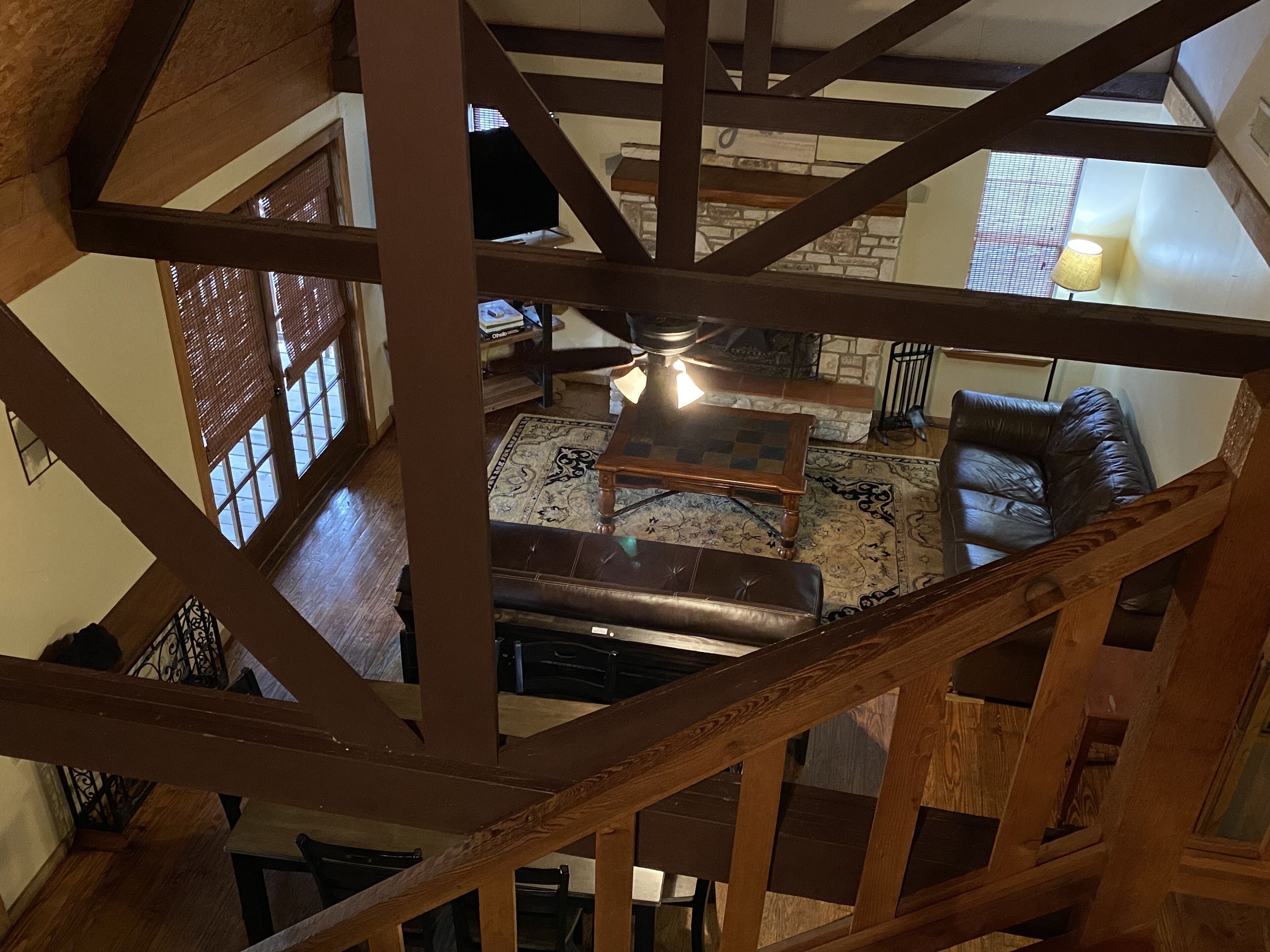 A wooden staircase with a view of a living room. The room has a fireplace, a sofa, and a coffee table.