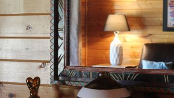 Un interior de madera que muestra un espejo reflejando una lámpara, una silla, una figurita y un cuenco sobre una estantería.